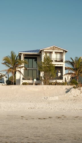 Florida beach house seen from the sand with palm trees and clear sky