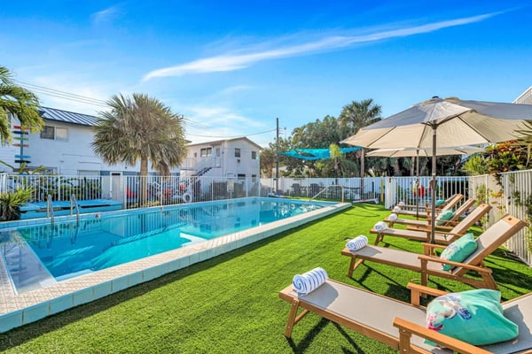 Pool with lounge chairs and palm trees at a Lauderdale-by-the-Sea property