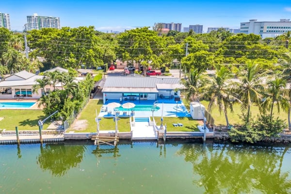 Aerial view of waterfront pool home with dock and canal
