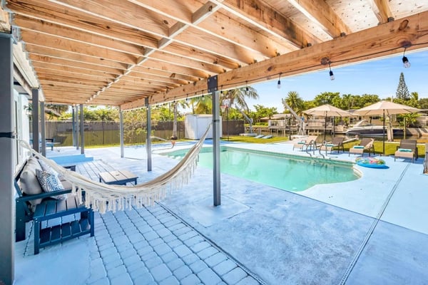 Covered patio with hammock overlooking pool and waterway